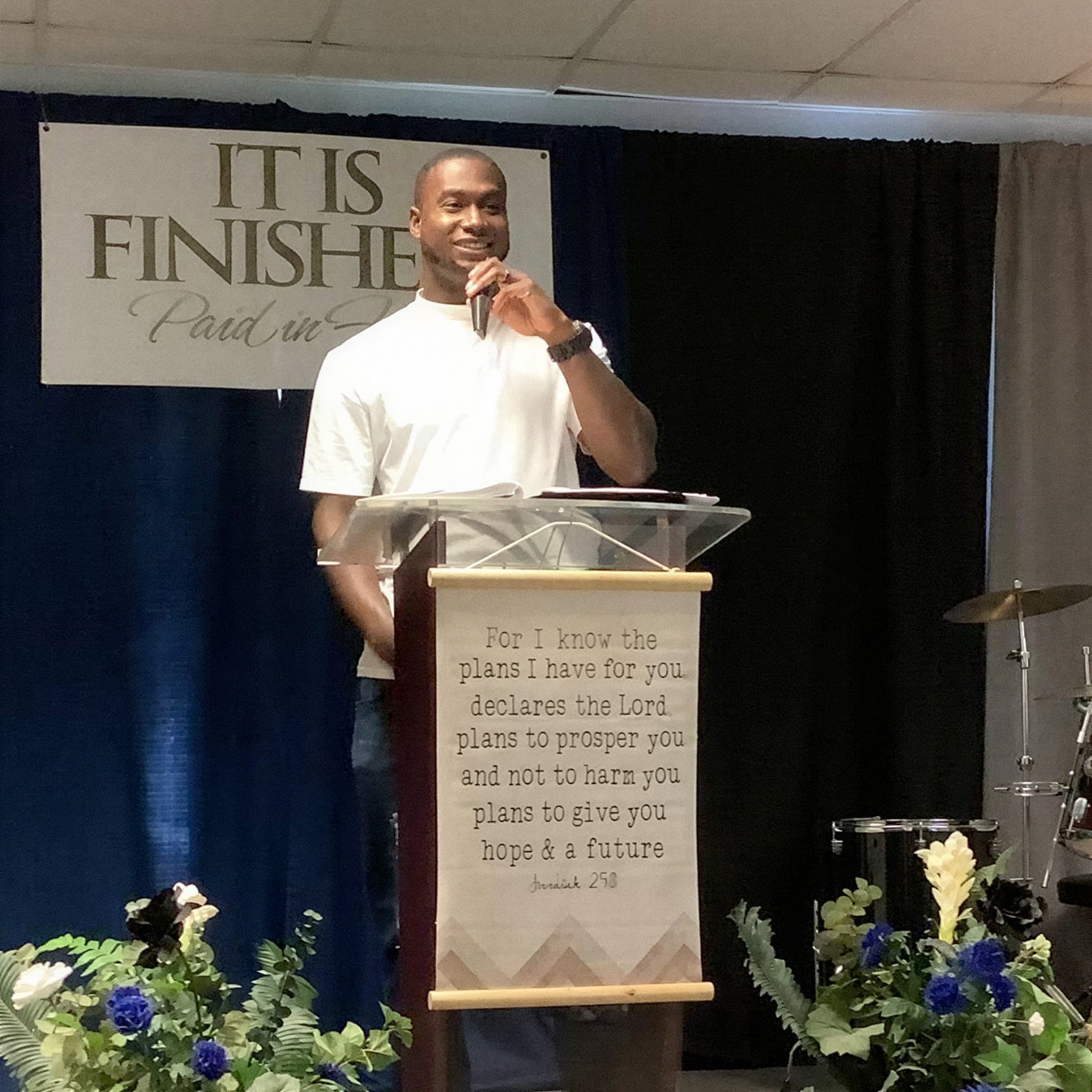 A speaker at the pulpit at See His Face Ministries, beneath a banner reading It Is Finished
