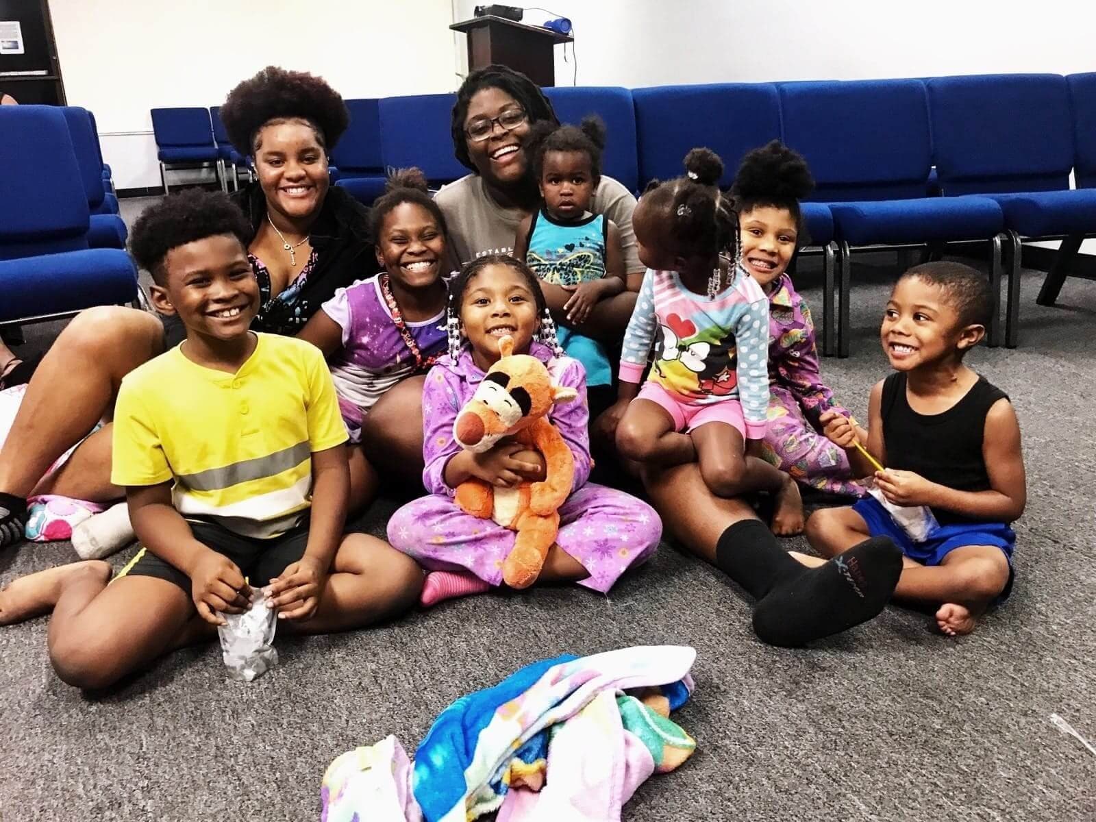 Young children in pyjamas sitting on the floor with their leaders at a See His Face Ministries lock-in
