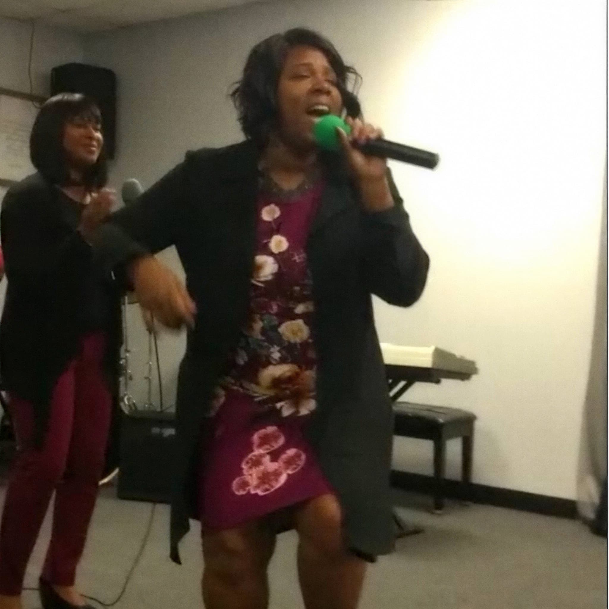 Two worship leaders singing into microphones during a service at See His Face Ministries