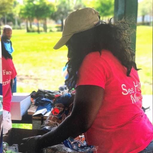 A See His Face Ministries volunteer sorting supplies at an outdoor table during a Seeds of Kindness outreach