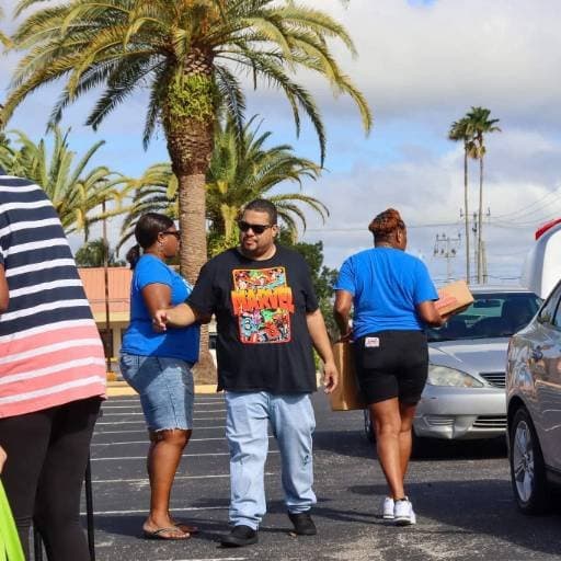 Volunteers carrying boxes out to waiting cars during a See His Face Ministries distribution outside the church